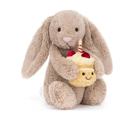 Plush bunny holding a small cake with a candle on a white background